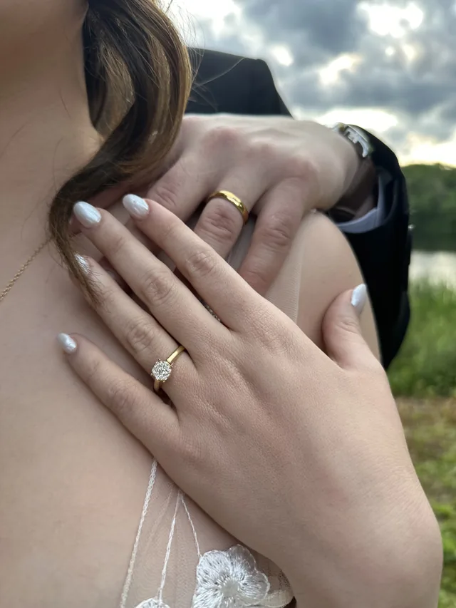 Two hands resting together, wedding bands and an engagement ring.