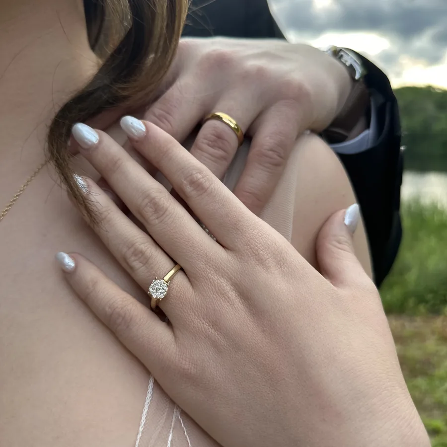 Two hands resting together, wedding bands and an engagement ring.