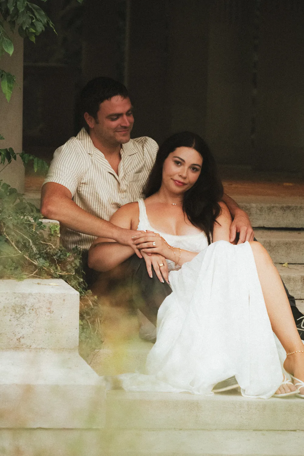 A couple sitting close together on stone steps in warm light.
